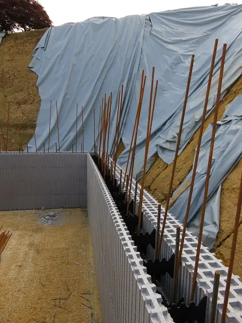 Les premières rangées de blocs sont posées... les barres à béton verticales sont en place... nous pouvons continuer à monter les murs de notre sous-sol