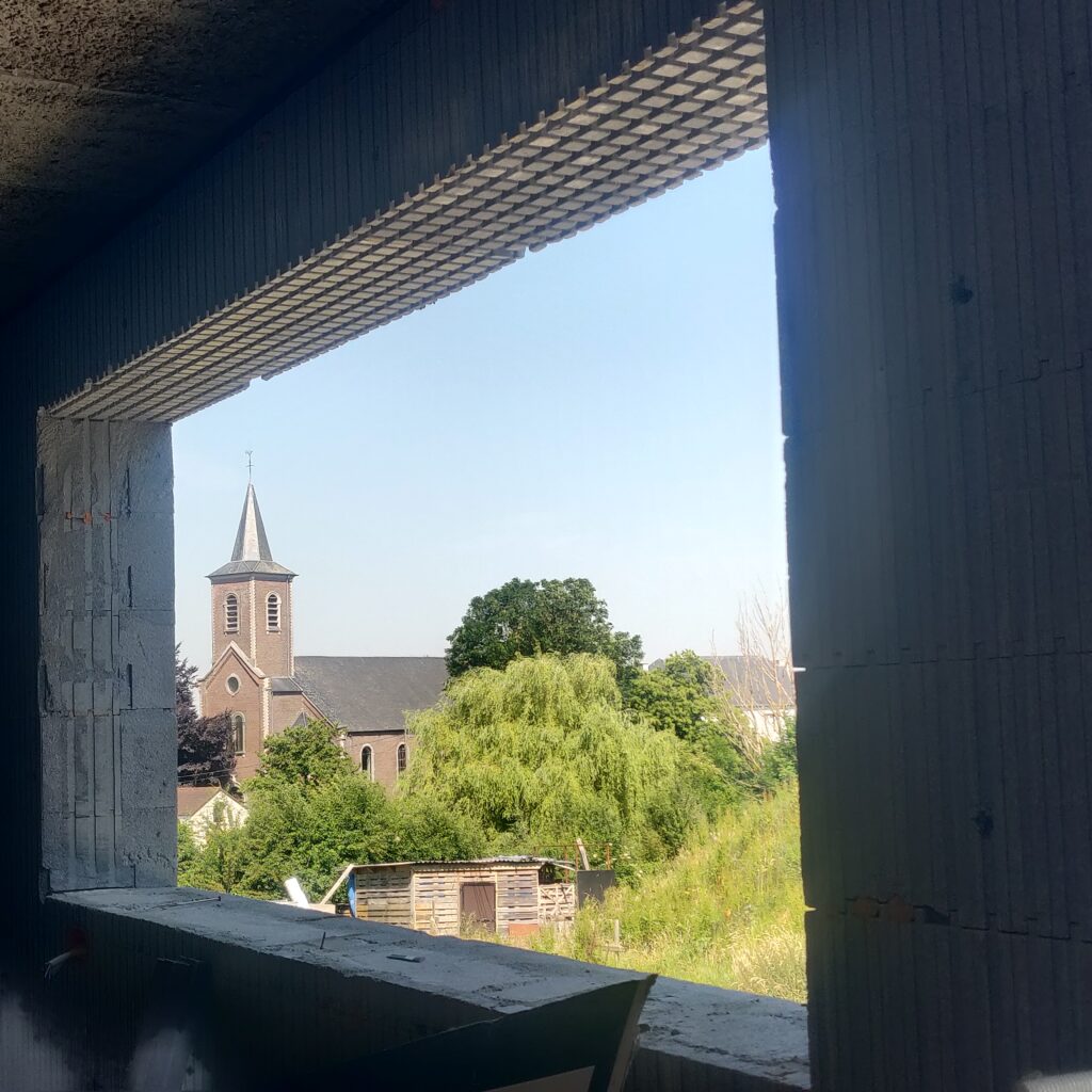 Groot raam met zicht op de kerktoren.