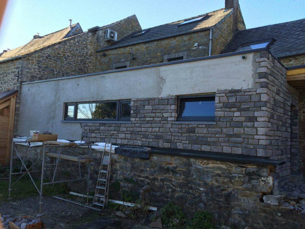 Hier is het plaatsen van de natuursteen al goed begonnen op de achtergevel.