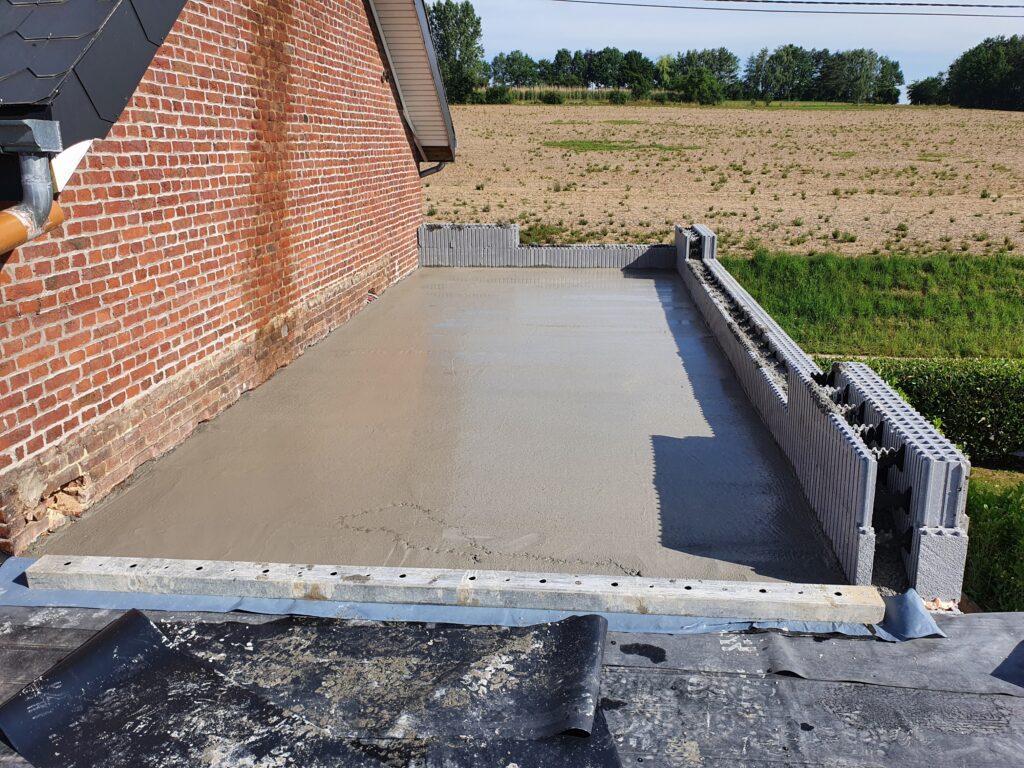 Hier is de vloerplaat van de verdieping gestort op de isolerende gewelven en de blokken rechts en achteraan, die zowel voor de bekisting als voor de voortzetting van de bouw van de muren van de verdieping hebben gediend.