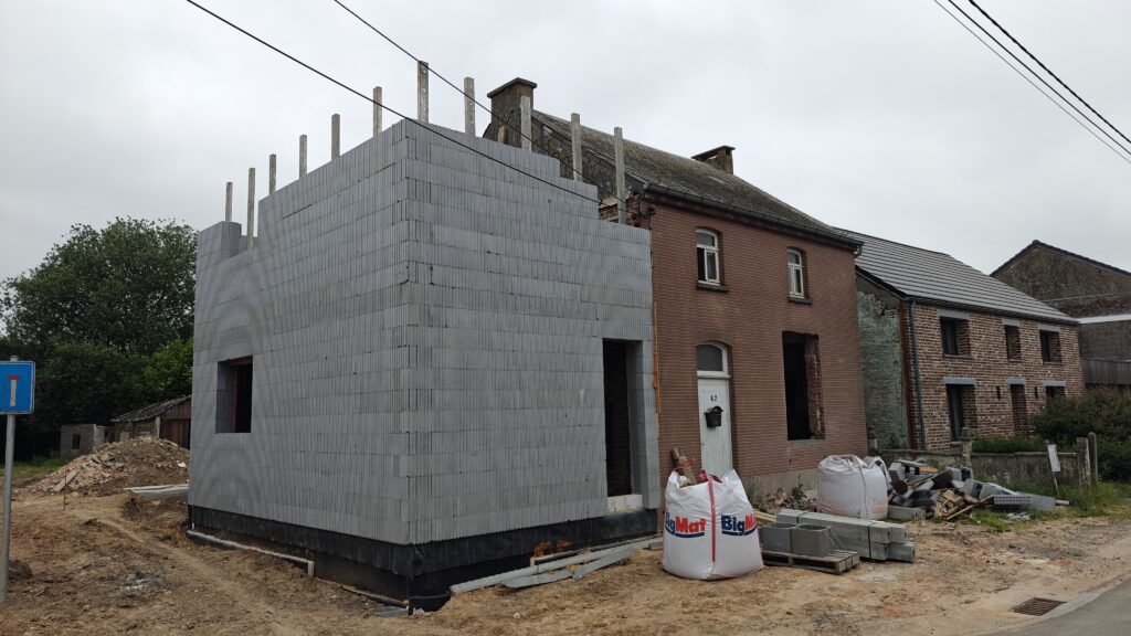 Cette photo montre clairement notre double chantier. Depuis la rue, vous voyez l'habitation que nous rénovons. C'est sur la droite. À gauche, les blocs de coffrage isolants de l'extension sont visibles. C'est un aspect clé de notre projet de vie.